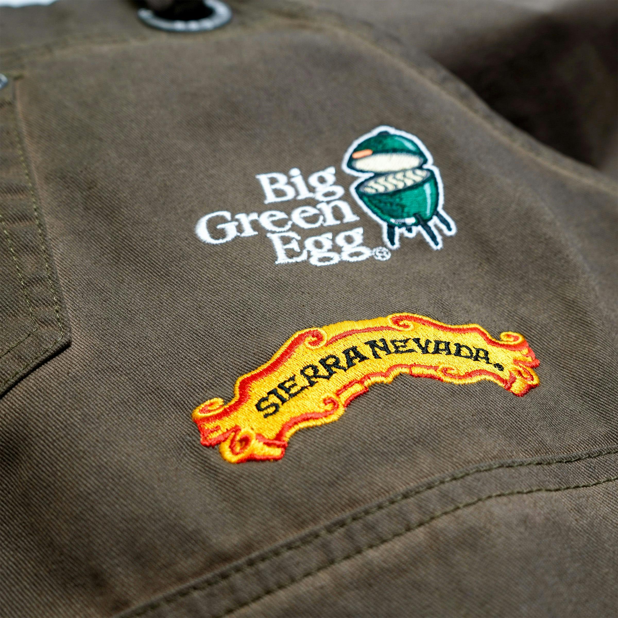 Close up angled view of the two embroidered brand logos on the Sierra Nevada Big Green Egg Grilling Apron