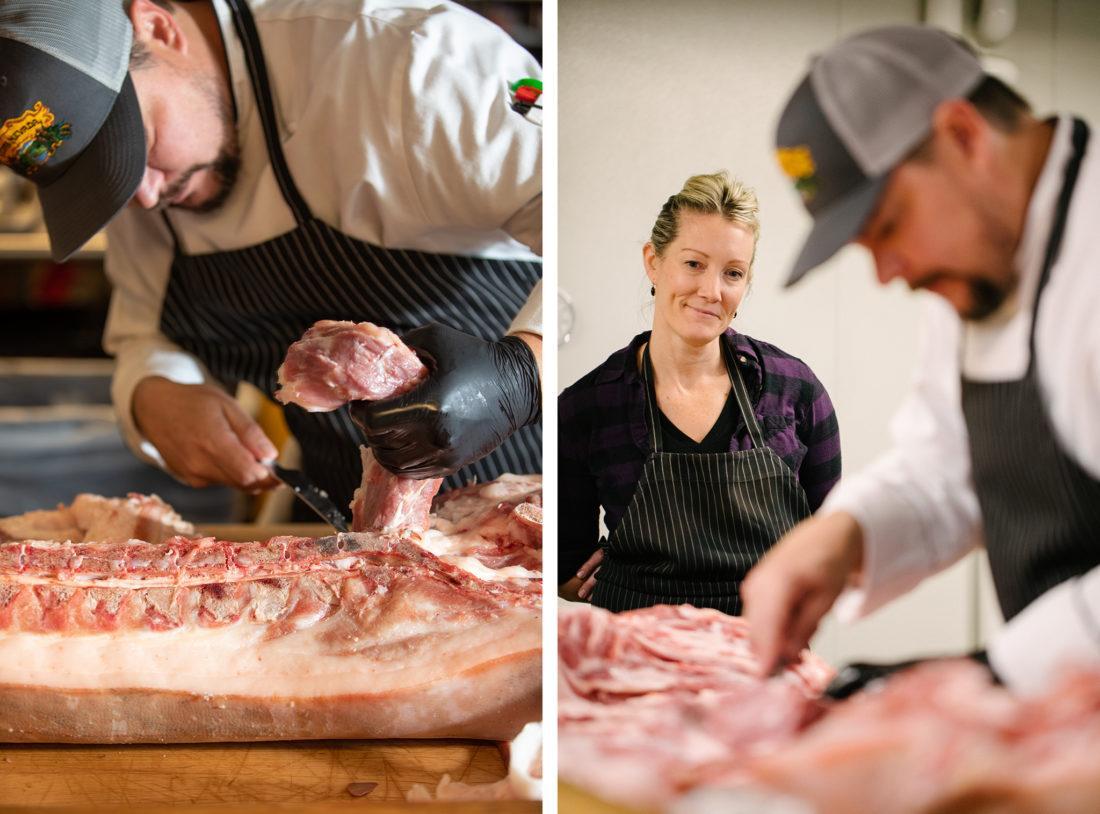 a cook cutting meat while a lady looks over his work