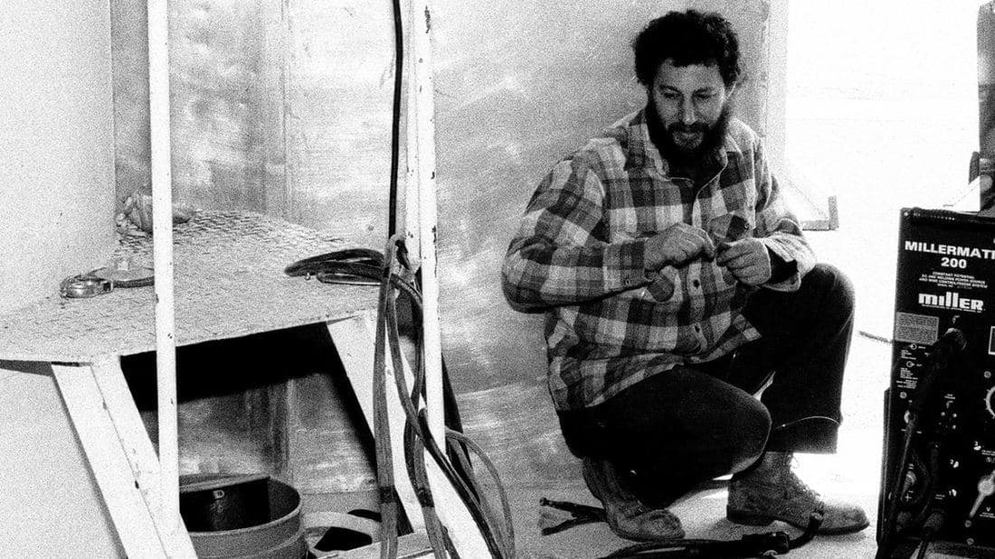 Sierra Nevada founder Ken Grossman circa 1982 kneeling next to brewery equipment