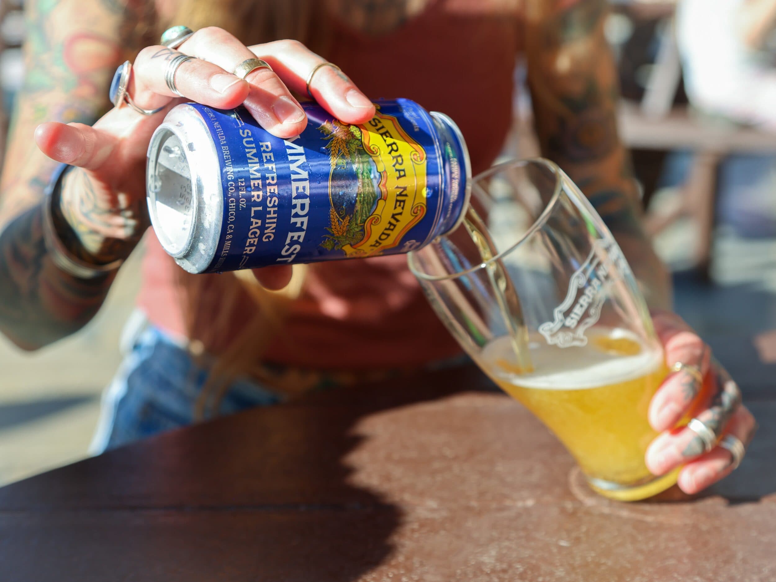 Can of Summerfest being poured into pilsner glass on table