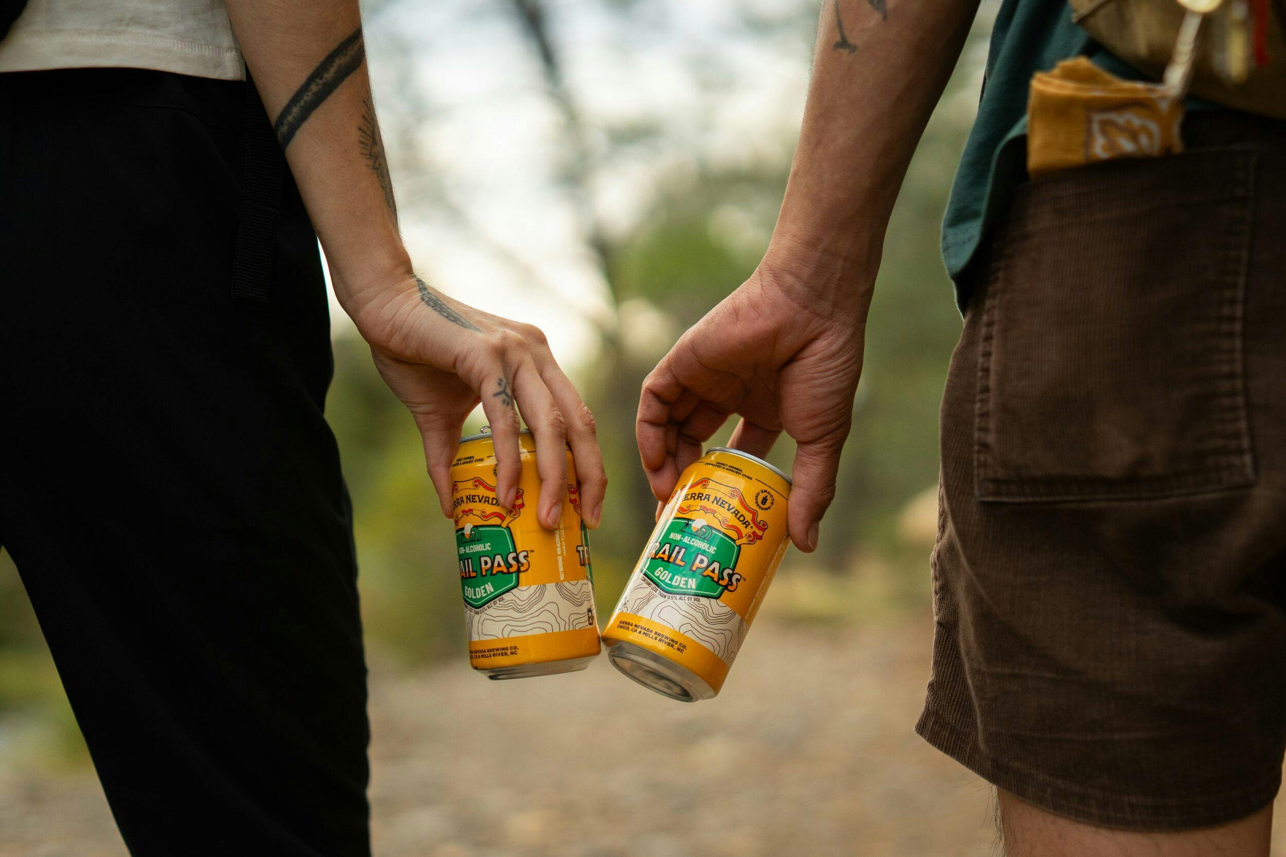 Trail Pass cans being cheersed outside