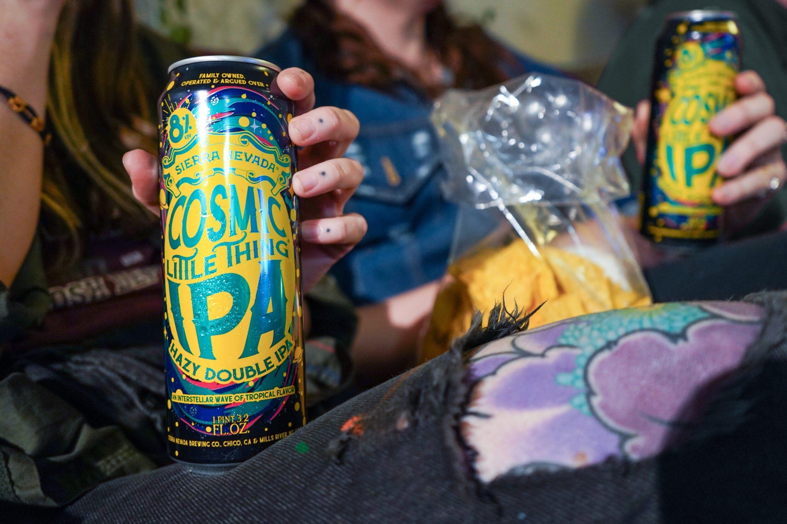 Cosmic Little Thing cans held by friends sitting on couch