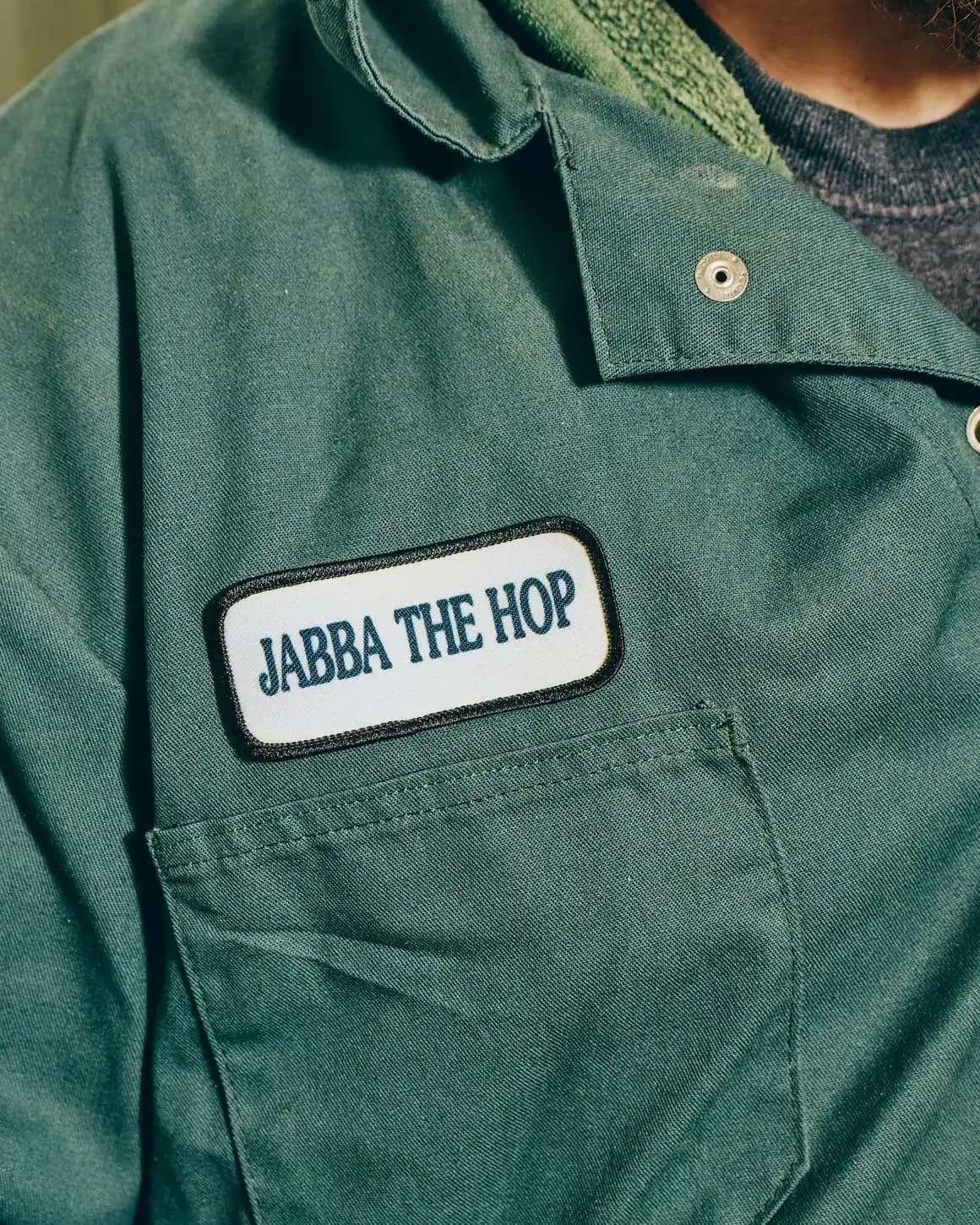 White name tag on green shirt that reads 'Jabba the hop'